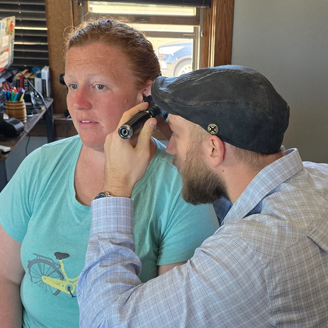 Dr. Jacob Stoffel uses medical tools to examine the inside of a patient's ear