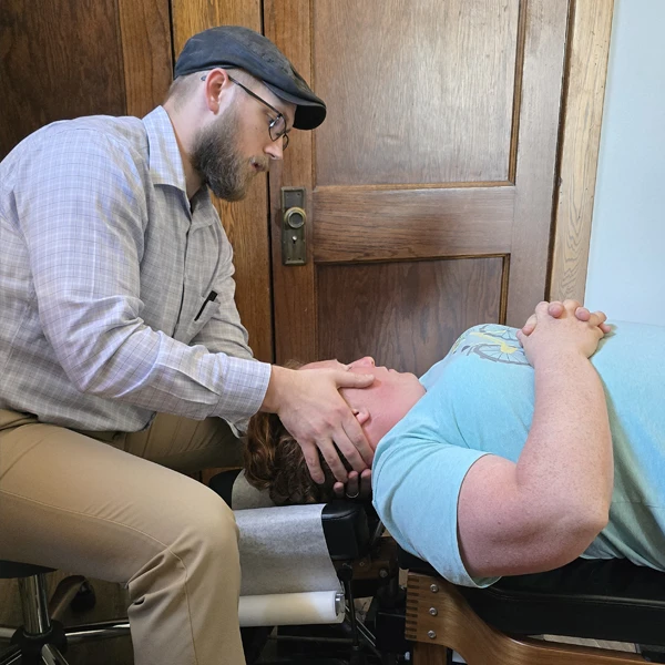 Dr. Jacob Stoffel adjusts a patient's neck while they lay on an adjustment table